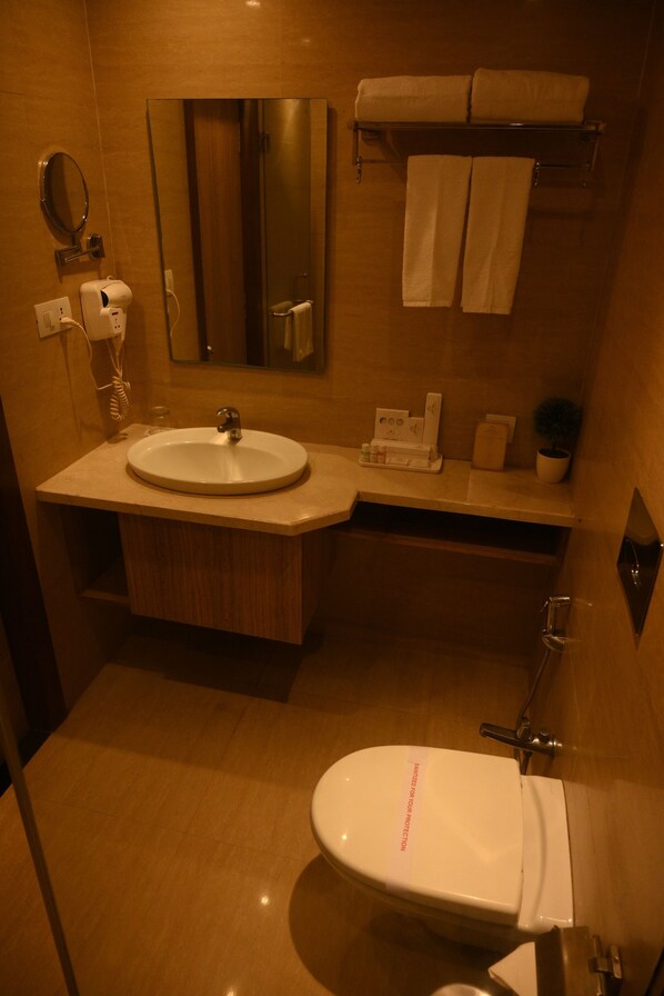 Une salle de bain moderne équipée d’un lavabo, d’un miroir, d’un porte-serviettes et de toilettes.