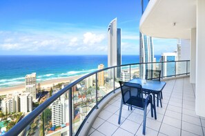 A balcony with a view of the ocean and cityscape.