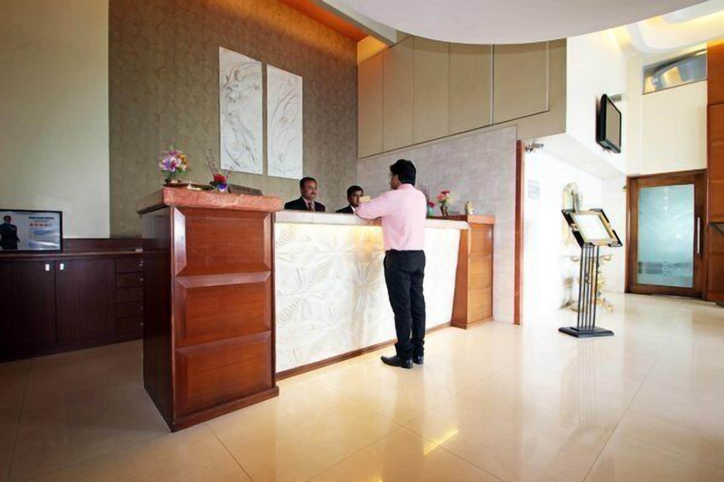A hotel reception area with a wooden reception desk, a large framed artwork on the wall, and a modern interior design.