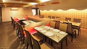 A conference room with a long table, multiple chairs, and a high ceiling with recessed lighting. - HOTEL SEVEN HEAVEN (Nashik)