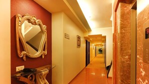 A hotel corridor with a marble floor, a large ornate mirror, and a reception desk. - HOTEL SEVEN HEAVEN (Nashik)
