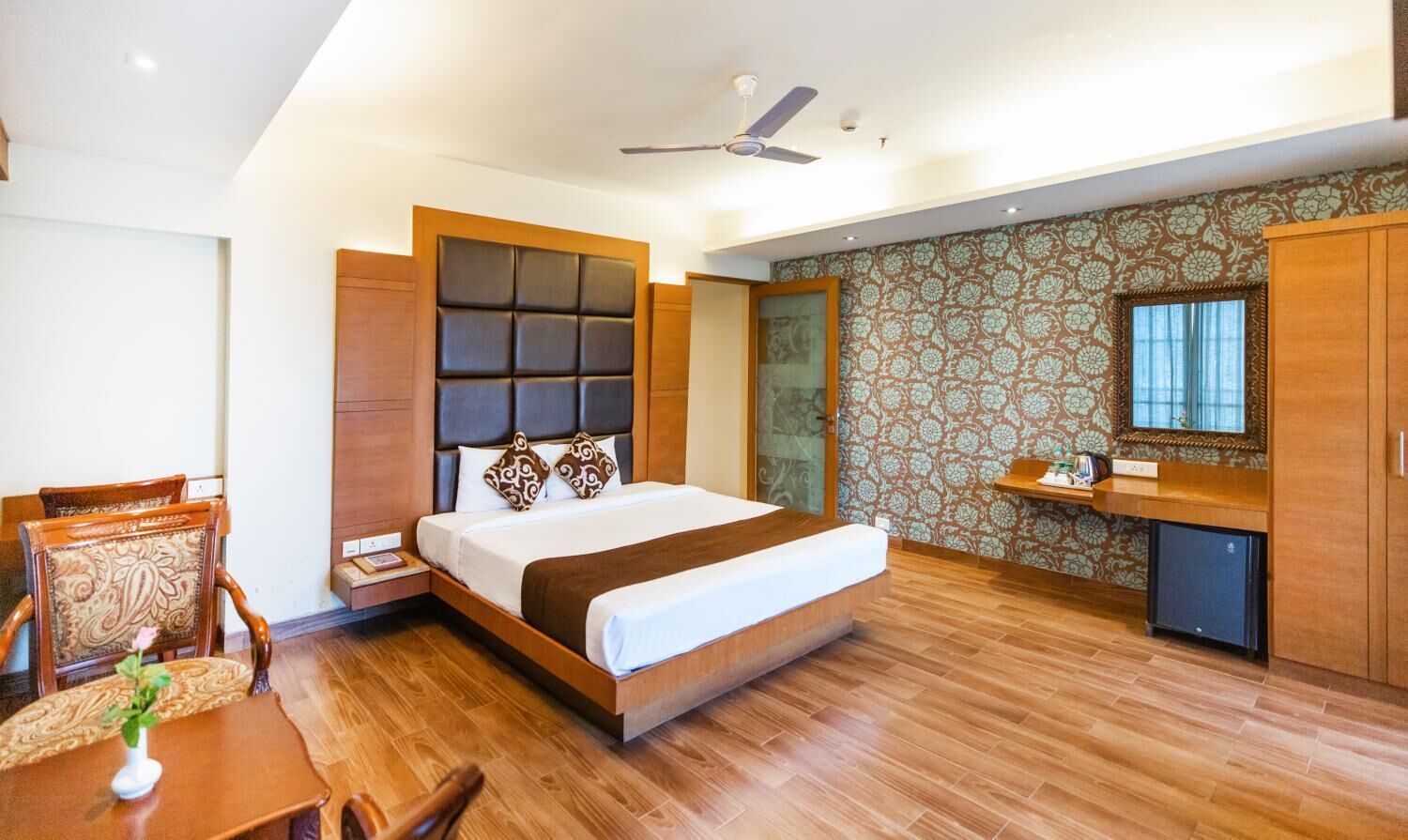 Una habitación de hotel moderna con una cama grande, un cabecero de madera, un escritorio y un armario.