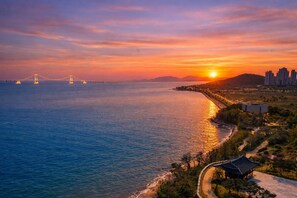 A coastal sunset view with a bridge, buildings, and a traditional pavilion. - Western Grace Hotel (Incheon)