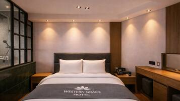 Una habitación de hotel con cama, mesitas de noche, escritorio y zona de ducha.