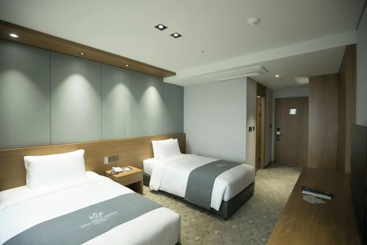 Habitación de hotel con dos camas, cabecero de madera, escritorio y piso alfombrado.