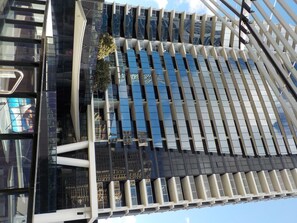 Un edificio moderno con fachada de vidrio reflectante y varias terrazas.