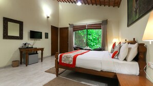 Un dormitorio con cama, escritorio, televisor y ventana con cortinas.