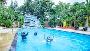 Una piscina con un telón de fondo de formaciones rocosas, rodeada de exuberante vegetación.