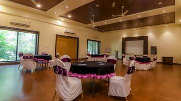 A conference room with round tables, white chairs with purple sashes, and a large screen.