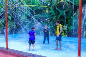 A water play area with a netted structure and people playing. - Jharna Resort (Chandrapur)