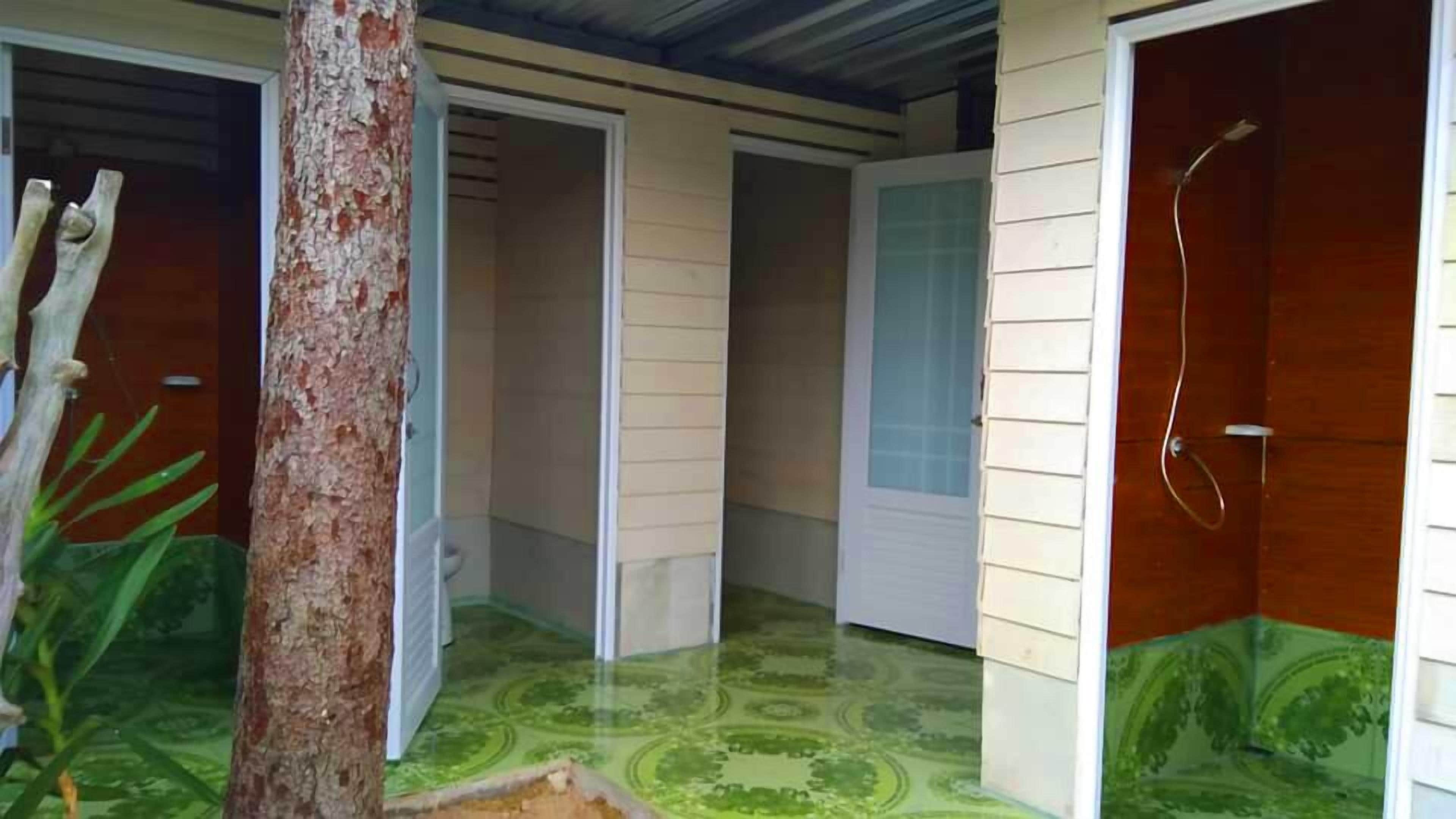 Una habitación con puerta de madera, zona de ducha y suelo estampado.