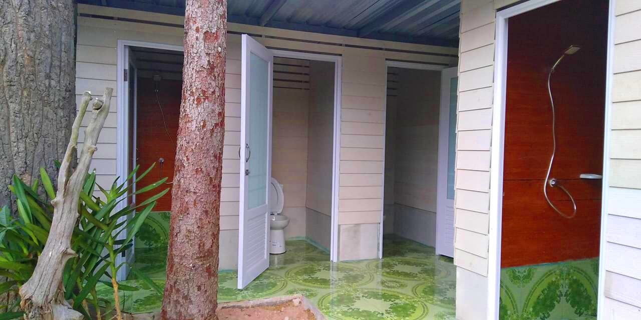 Un baño con dos puertas, una que da a un inodoro y otra a la zona de la ducha.