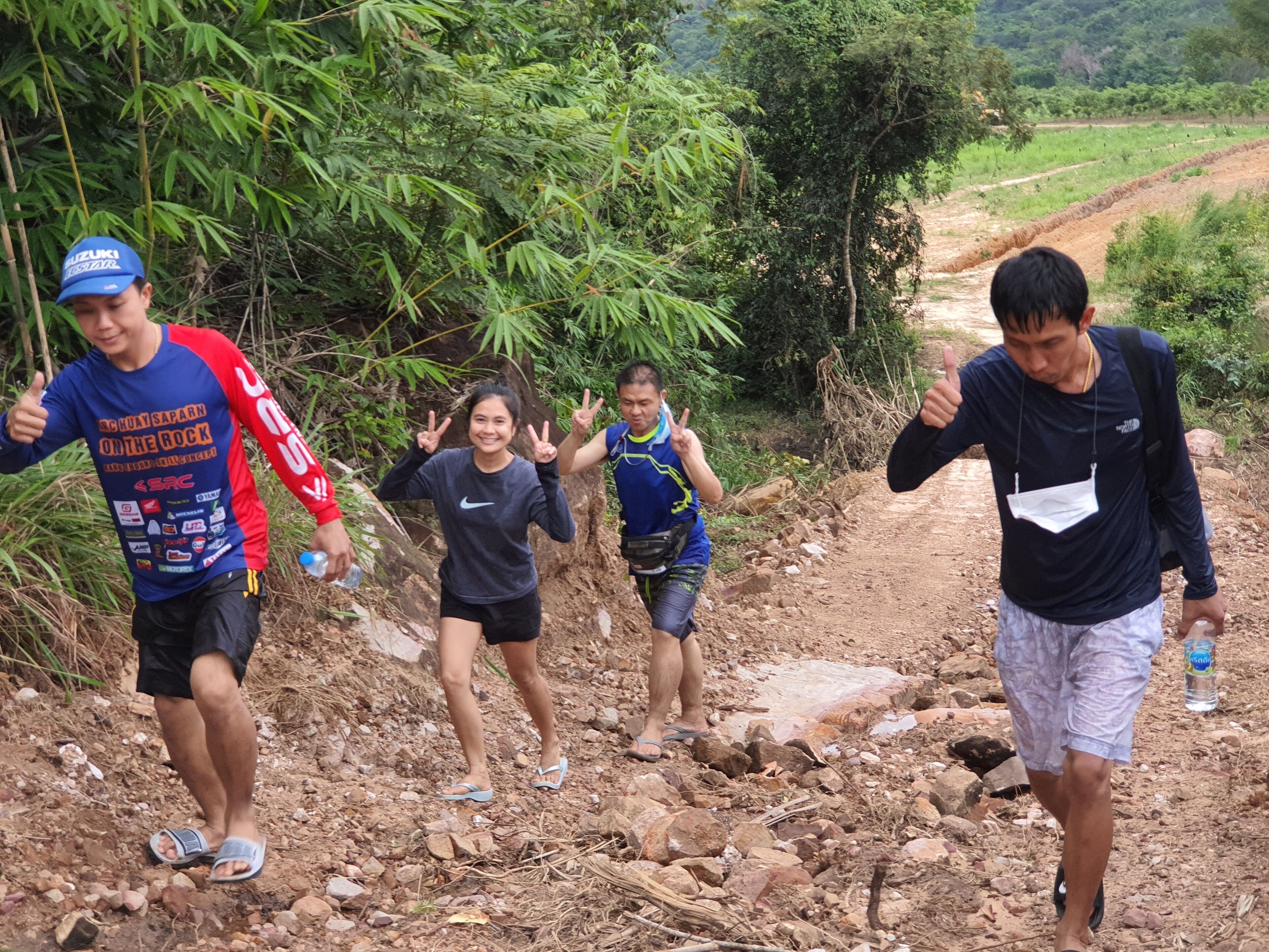 A group of people hiking on a rocky trail surrounded by greenery.