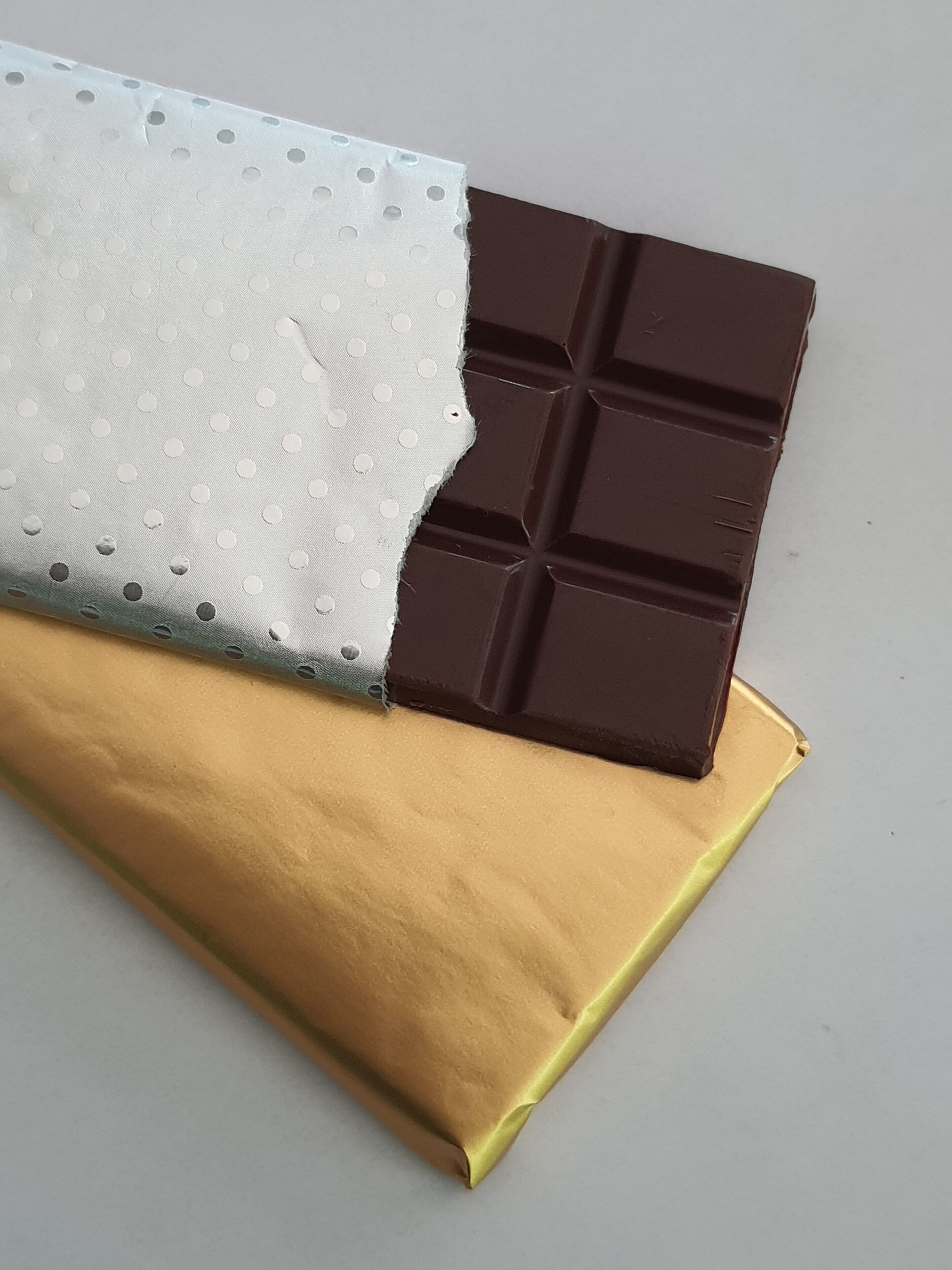 A chocolate bar partially wrapped in a golden foil package.