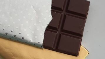 A chocolate bar partially wrapped in a golden foil package.