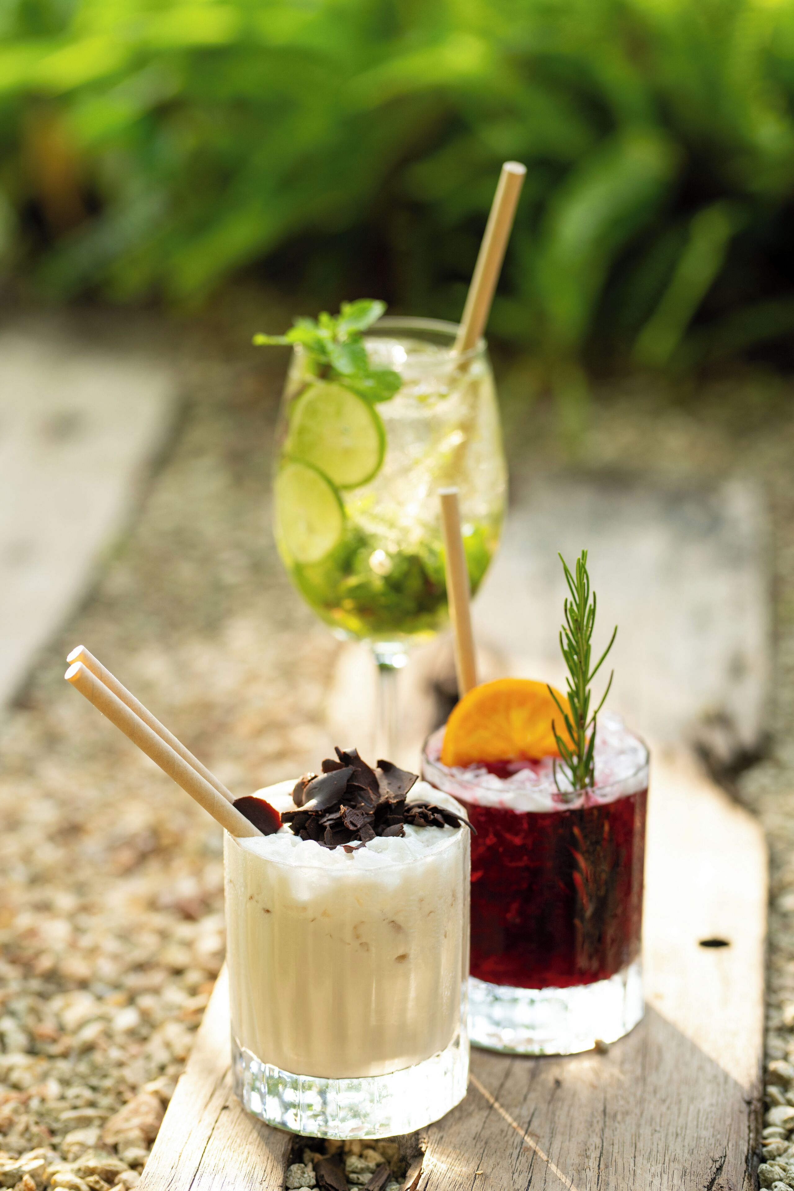 Two drinks on a wooden table with a blurred green background.