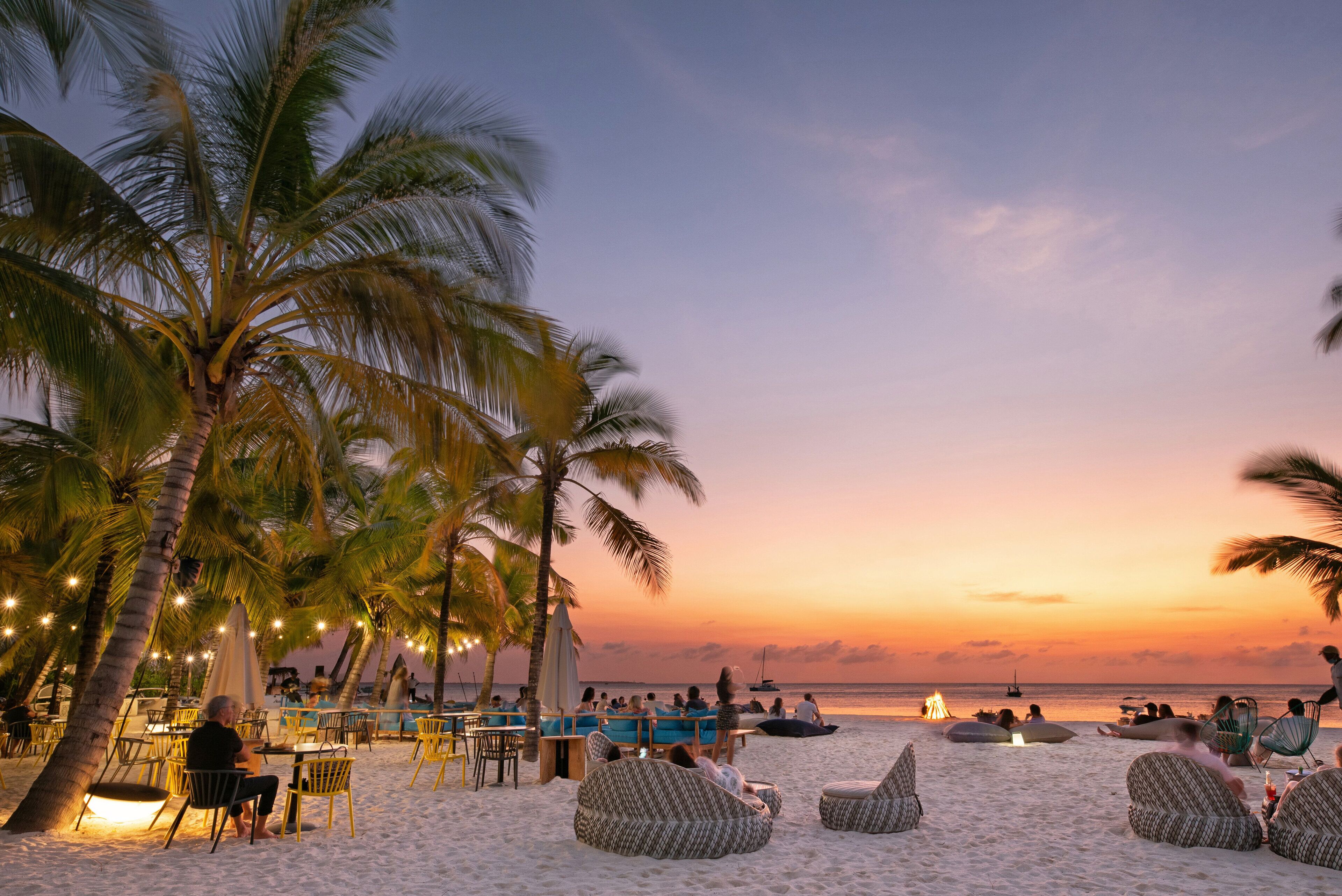 Eine Strandbar mit Sitzgelegenheiten im Freien und Palmen.