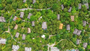 An aerial view of a resort with thatched-roof cottages, lush greenery, and a swimming pool. - Zuri Zanzibar (Kendwa)