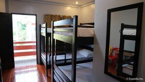 Una habitación con literas, piso de madera y una ventana con cortinas.