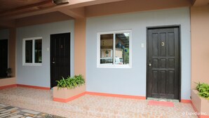 Un edificio con dos puertas negras, una ventana y un área de entrada con azulejos.