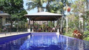 A swimming pool with a covered seating area and surrounding tropical vegetation. - Away on Shirley Lane (Byron Bay)
