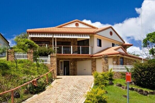 A two-story house with a stone facade, a balcony, and a white picket fence.