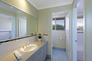 A bathroom with a sink, mirror, and a window.