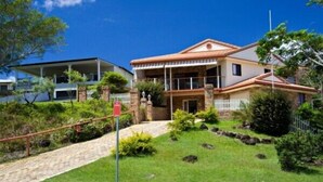A two-story house with a balcony, surrounded by a well-maintained garden and a white picket fence. - Away on Massinger Street (Byron Bay)