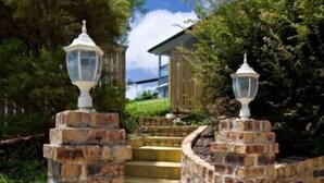 A set of stone steps leading up to a building entrance, flanked by brick walls and topped with lantern-style lights. - Away on Massinger Street (Byron Bay)