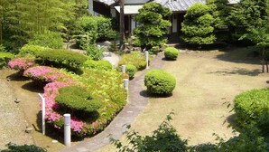 A traditional Japanese-style building surrounded by well-maintained gardens with various shrubs and flowering plants. - Beppu Housensou (Beppu)