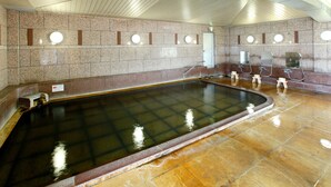 A large indoor pool with a tiled floor and walls, equipped with multiple shower stations. - Beppu Housensou (Beppu)