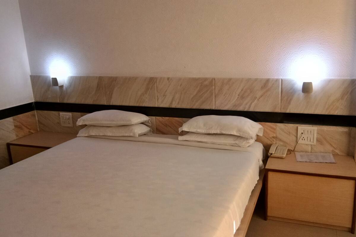 A hotel room with a bed, two bedside tables, and two wall-mounted lights.