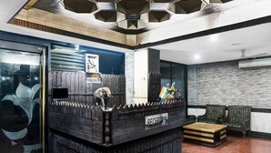 A reception area with a wooden reception desk, a '12 NO CHECK OUT' sign, and a reception counter. - Hotel Arch Manor Deluxe (Bhopal)