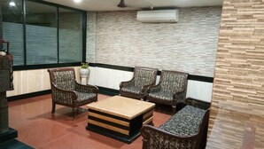 A room with a sofa set, a coffee table, and a decorative vase with flowers. - Hotel Arch Manor Deluxe (Bhopal)