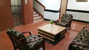A lobby with a marble-tiled floor, a staircase, and a reception desk with chairs. - Hotel Arch Manor Deluxe (Bhopal)