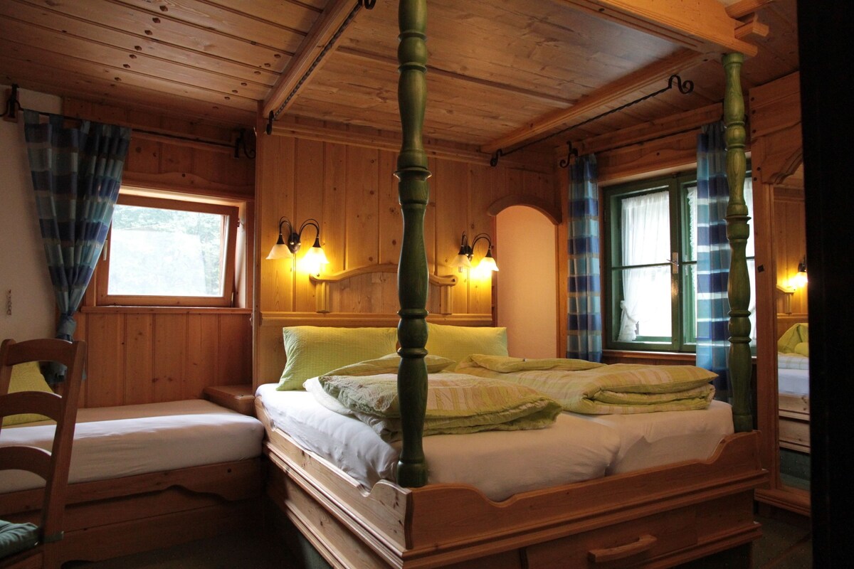 A wooden cabin bedroom with a four-poster bed, two bedside tables, and two wall-mounted lamps.