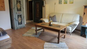 A living room with a wooden coffee table, a white sofa, and a blue cabinet. - Bei Herrmanns (Sautens)