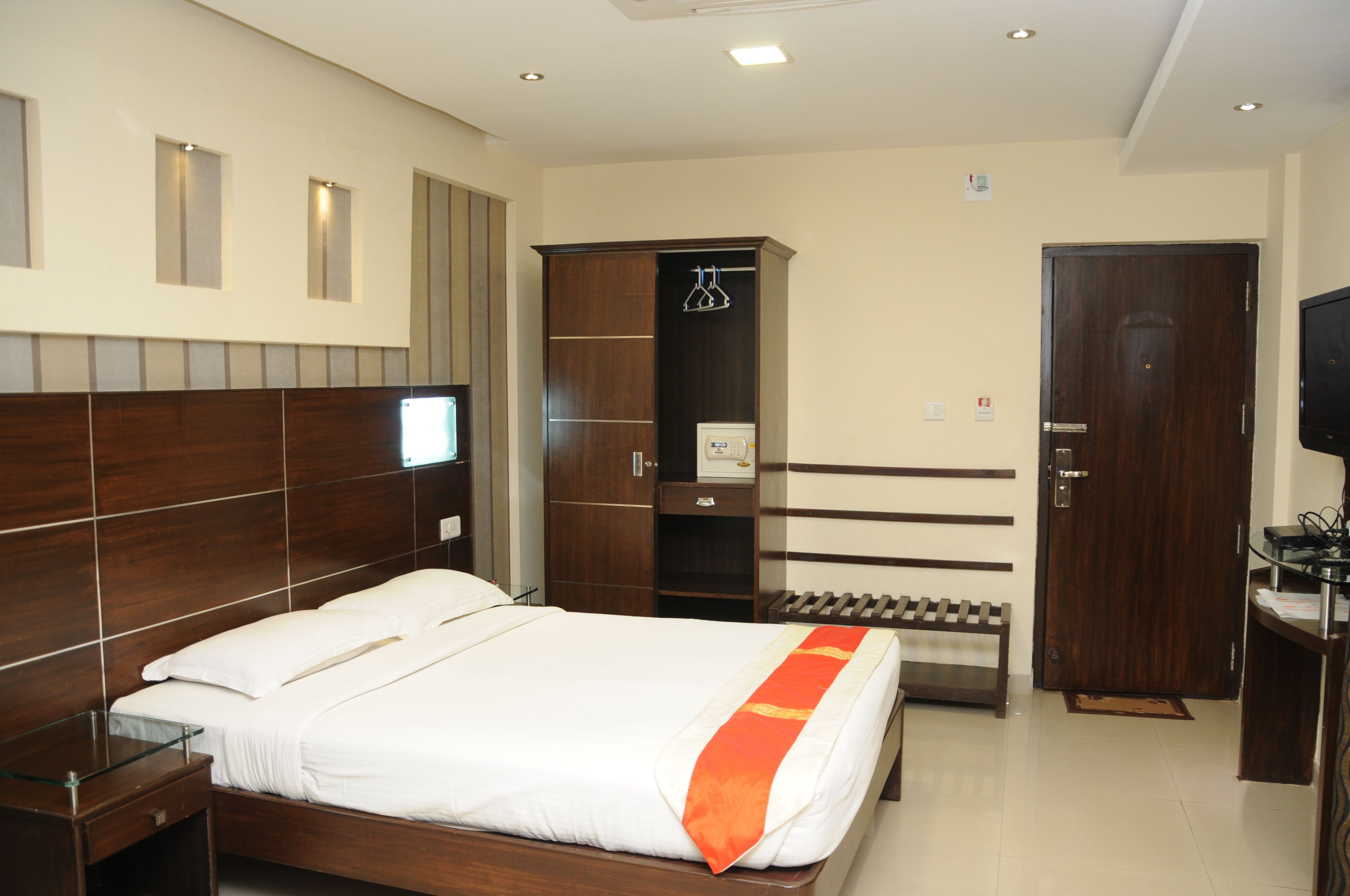 Ein Hotelzimmer mit Bett, Kleiderschrank, Schreibtisch und Fernseher.