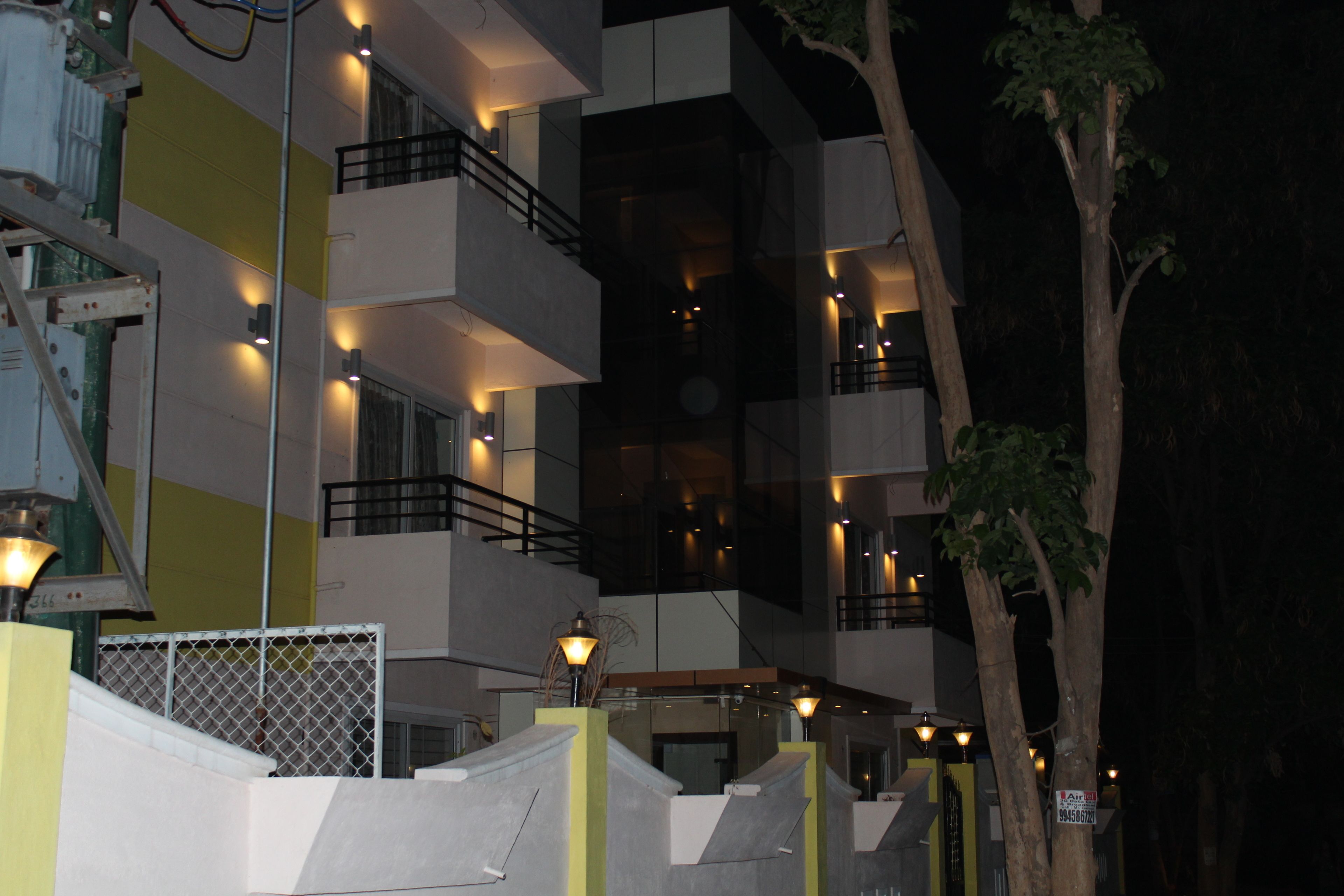 A multi-story building with balconies, outdoor lighting, and a tree.
