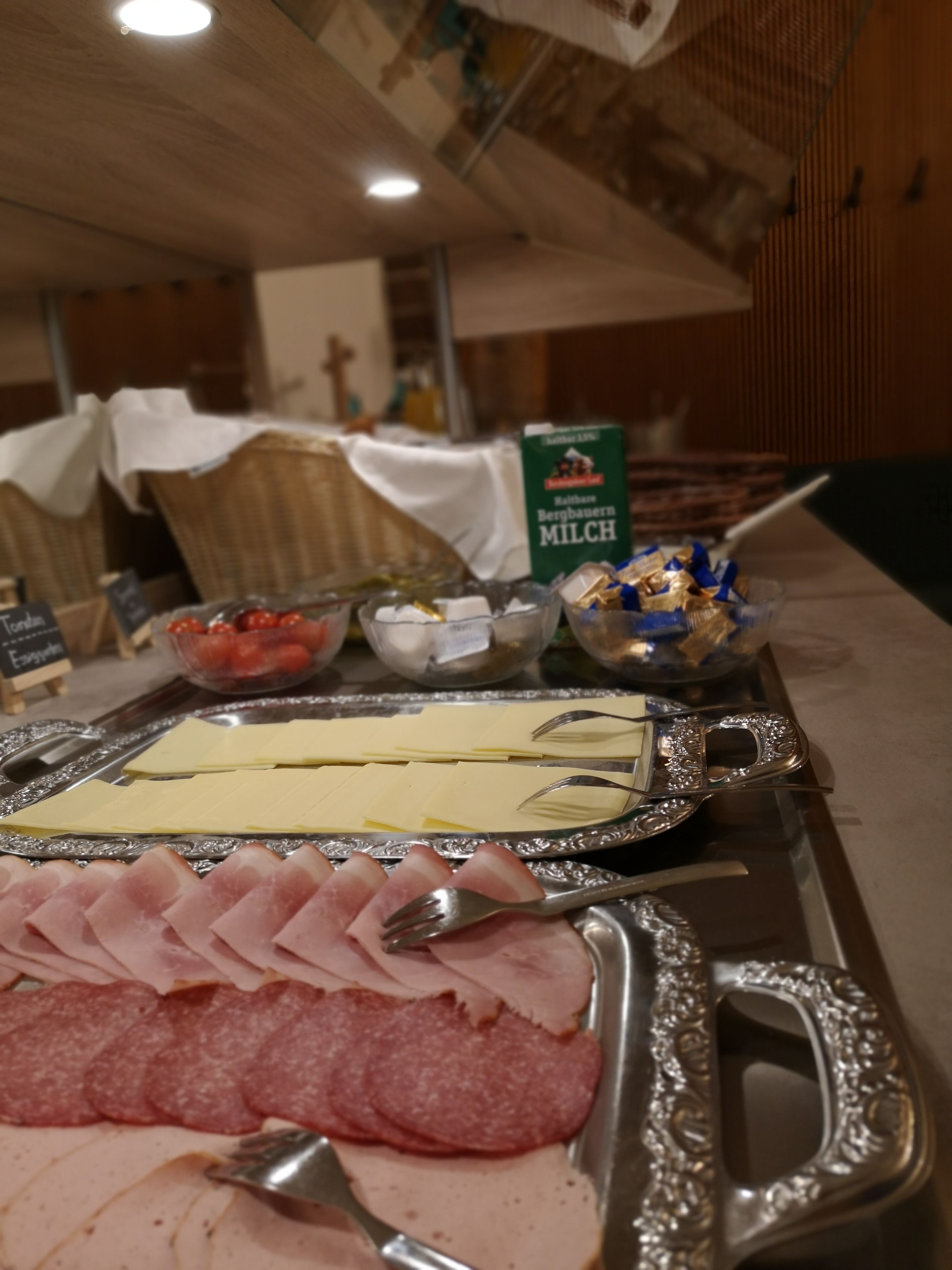 Een buffet met diverse etenswaren, zoals vleesschotels, kaas en een schaal aardbeien.