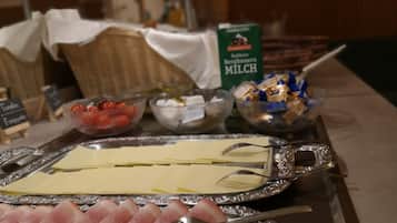 Een buffet met diverse etenswaren, zoals vleesschotels, kaas en een schaal aardbeien.