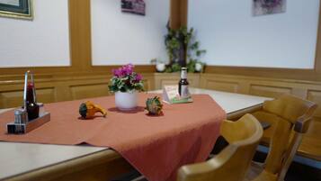 Una mesa de comedor con mantel rojo, una botella, una planta pequeña y un adorno.