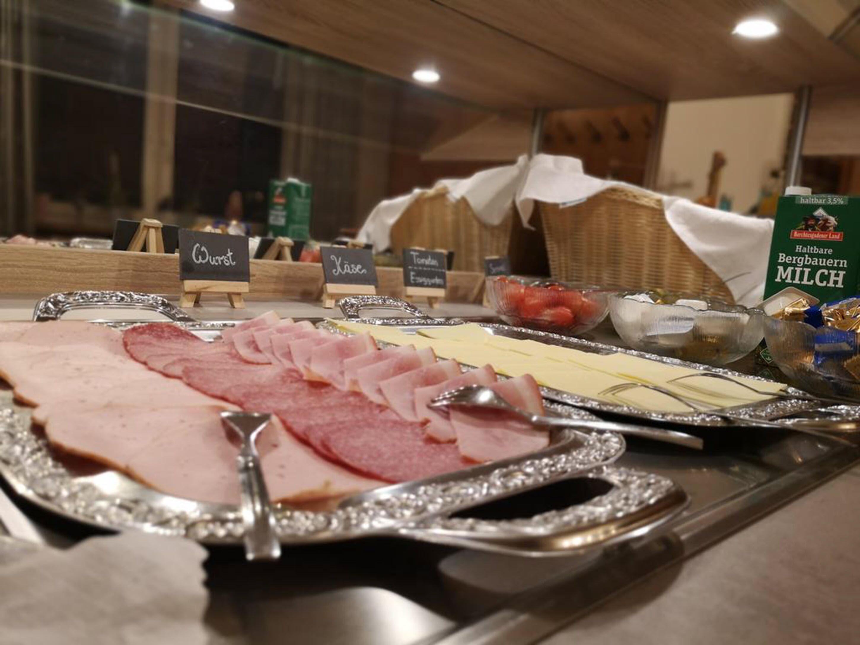 A deli counter with various meats and cheeses displayed on trays.