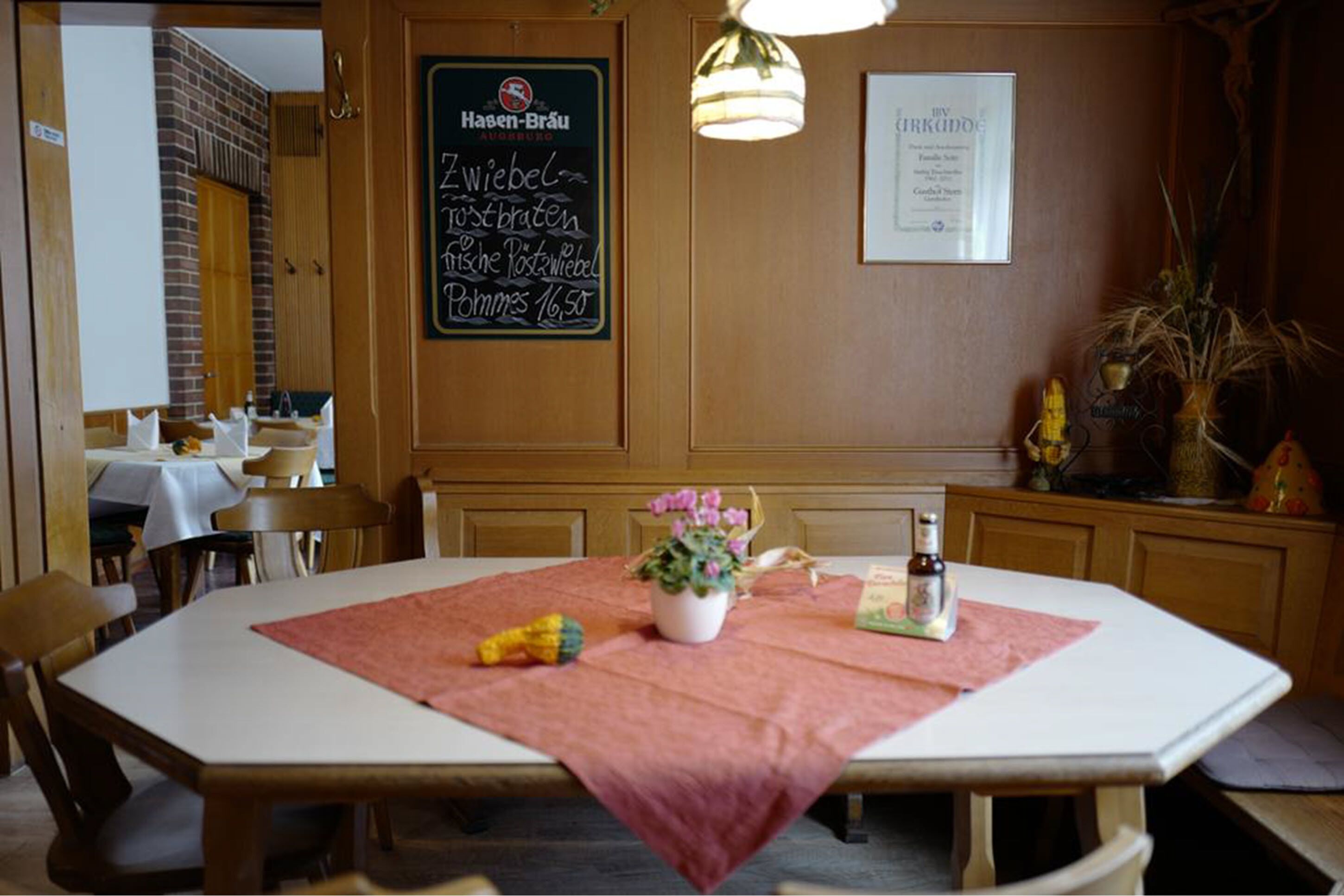 A restaurant interior with a table set for two, a chalkboard menu, and a framed certificate on the wall.