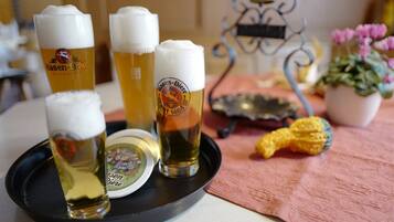 Four glasses of beer on a tray with a coaster, a metal stand, and a potted plant.