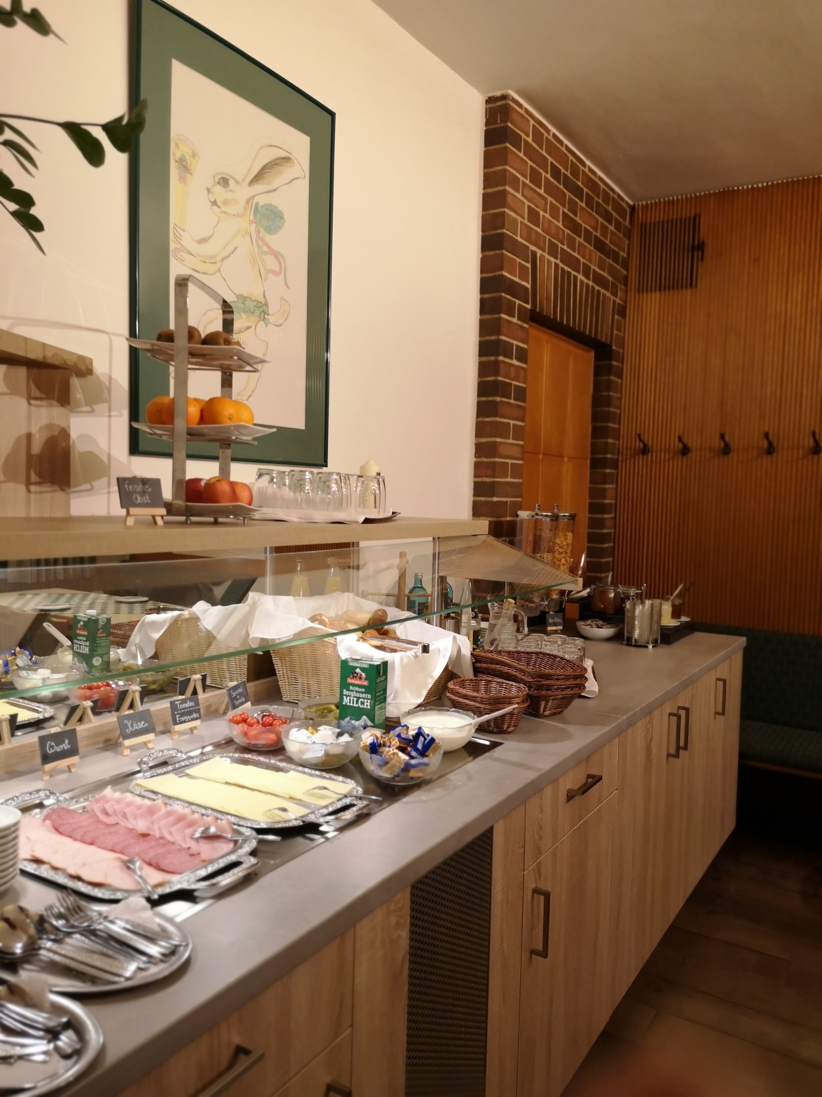 A buffet setup with various food items and beverages, including cheese, ham, and milk.