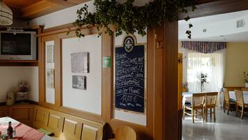 Interior acogedor de un restaurante con muebles de madera, un menú en una pizarra y vista al salón comedor.