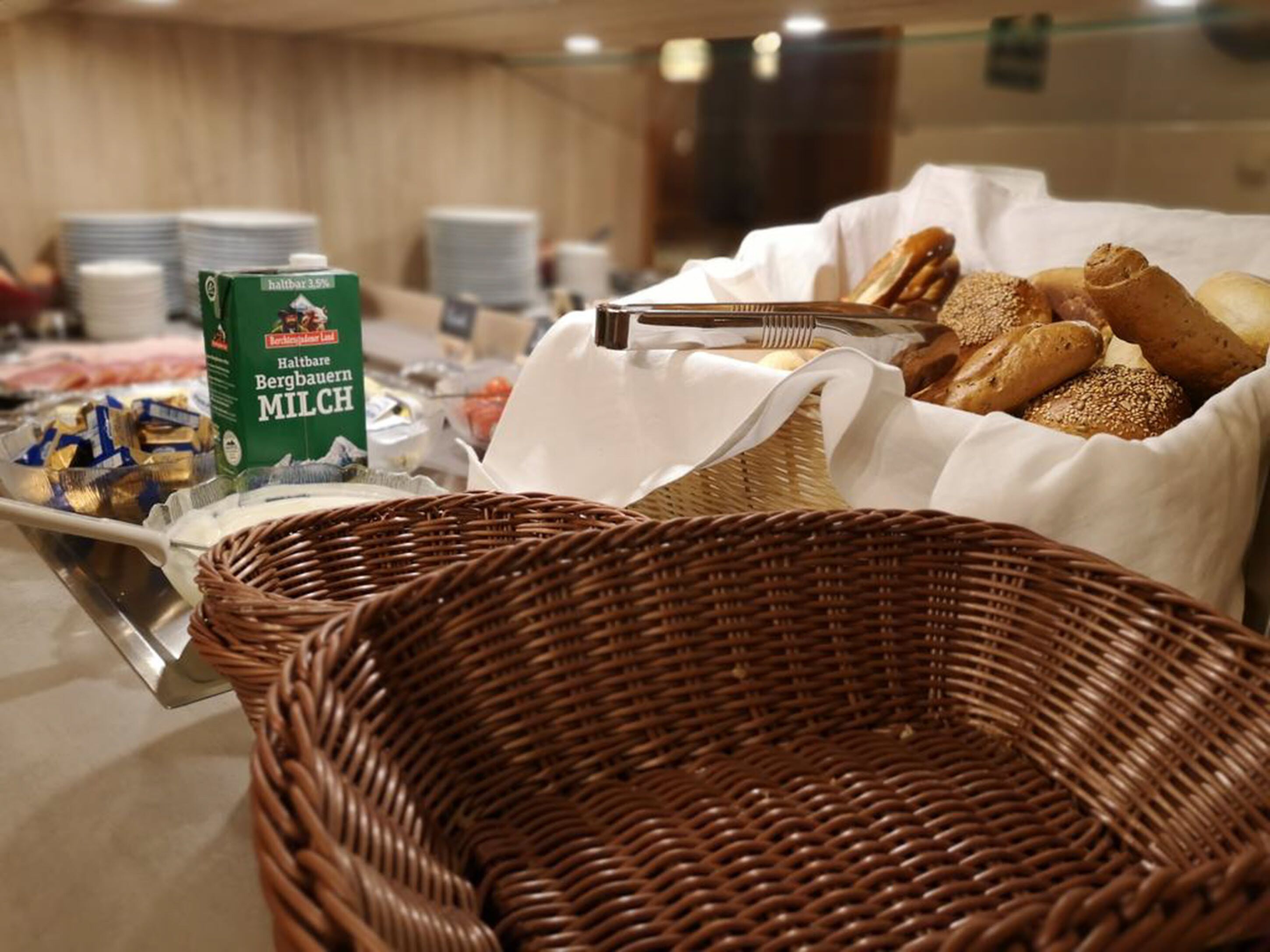 A buffet setup with various food items, including a carton of milk, bread, and pastries.