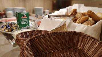 A buffet setup with various food items, including a carton of milk, bread, and pastries.