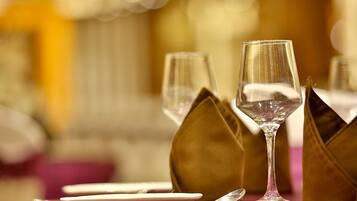 Una mesa servida con cristalería transparente, platos y una cuchara, con un fondo desenfocado que sugiere un ambiente de comedor formal.